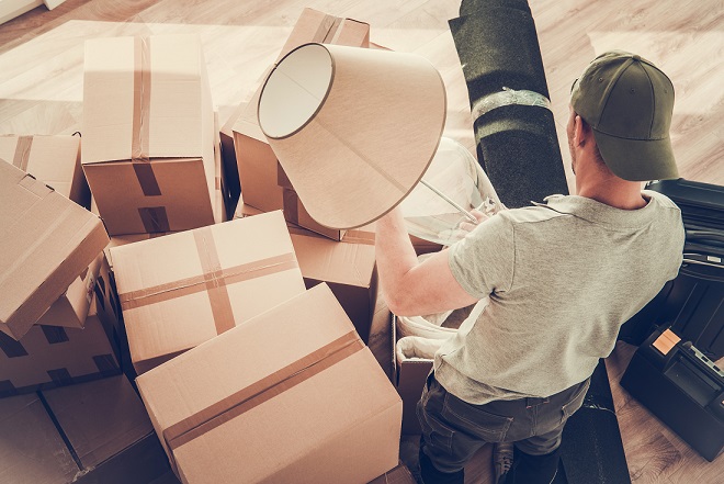 Caucasian Divorced Men in His 30s Moving Out From His Home. Staying Between Cardboard Boxes Preparing to Pack His Lamp.